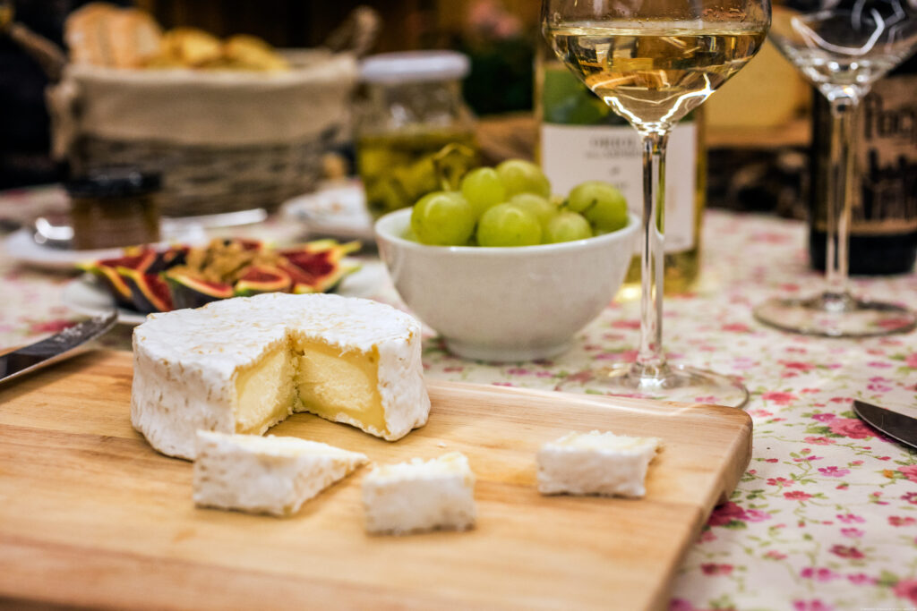 Ziegenkäse auf einem Holzbrett mit Wein, Trauben und Feigen, serviert auf einem rustikalen Tisch.